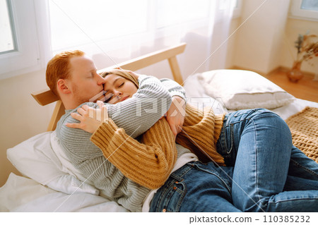 Couple in love relaxing at home on bed while they hug each other. Valentine's Day, holiday concept. Couple in love relaxing at home on bed while they hug each other. Valentine's Day, holiday concept. 110385232