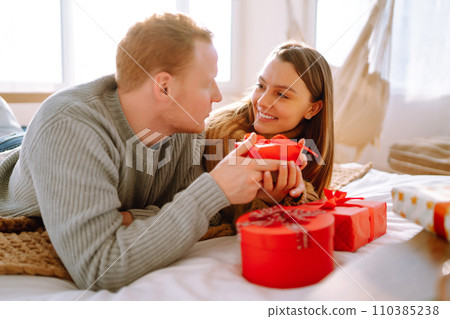 Valentine's Day concept. Exchange of gifts. Young couple at home celebrating Valentine's Day. 110385238