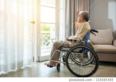 Lonely older thoughtful sad old man look outside windows in bedroom at retirement home, Asian senior man disabled feel depressed lonely sitting alone in wheelchair looking through window at hospital 110385393