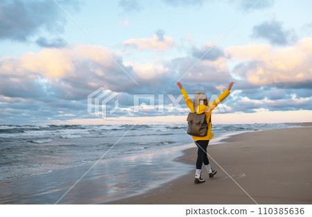 The girl tourist in a yellow jacket posing by the sea. Travelling, lifestyle, adventure. 110385636