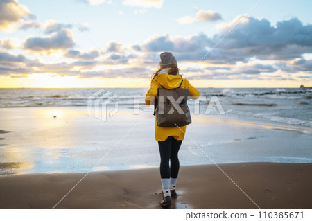 The girl tourist in a yellow jacket posing by the sea. Travelling, lifestyle, adventure. 110385671