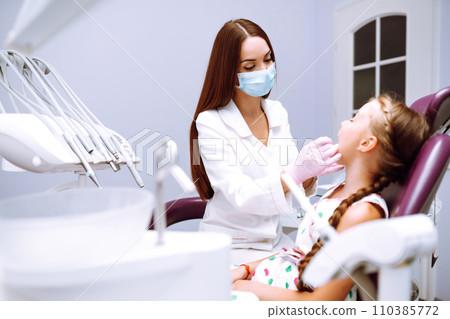 Lovely little girl smiling after doing examination in a pediatric stomatology. Milk teeth care. 110385772