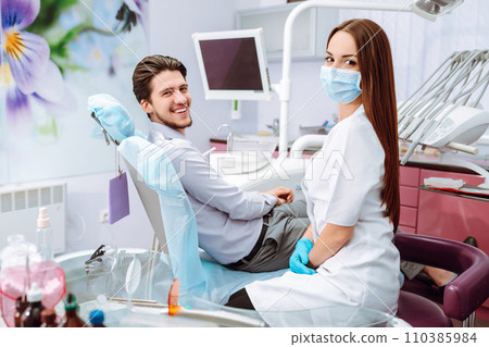 Young man at the dentist's chair during a dental procedure. Overview of dental caries prevention. 110385984