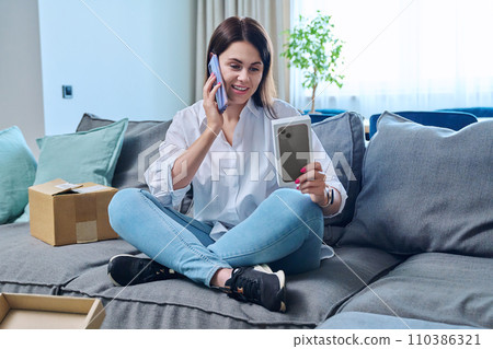 Young woman sitting at home unpacking cardboard box with online shopping Young woman sitting at home unpacking cardboard box with online shopping 110386321