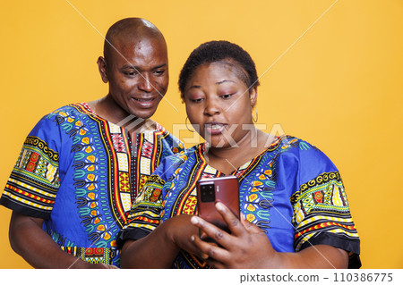 Mature man and woman romantic couple checking social media network on mobile phone. Wife holding smartphone in hand and showing online message on screen to shocked husband 110386775