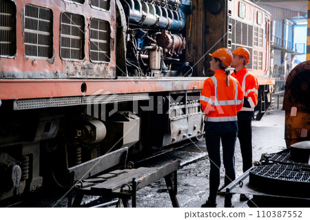 Young caucasian engineer man and woman check and maintenance engine of train in station. 110387552