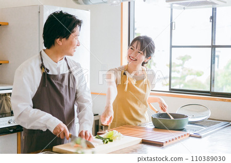 A couple cooking in the kitchen/A man cutting vegetables with a knife 110389030