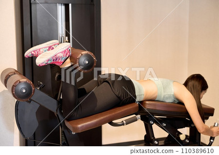 A woman training her legs with leg curls A woman training her legs with leg curls 110389610
