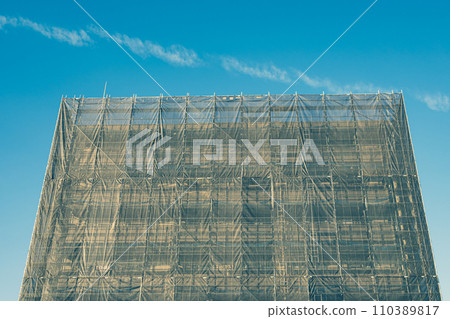 公寓大樓的大規模維修工作,固化窗簾和鷹架,強調暖色和冷色 公寓大樓的大規模維修工作,固化窗簾和鷹架,強調暖色和冷色 110389817