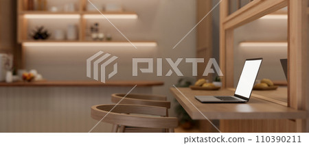 Side view image of a laptop computer on a wooden dining table in a modern, luxury dining room. 110390211