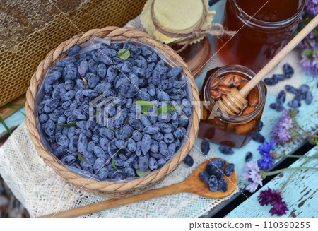 Still life with natural honey, honeycomb cut in pieces and honeysuckle berry with flowers on wooden background outside. Countryside summer rural background, vintage concept, healthy food Still life with natural honey, honeycomb cut in pieces and honeysuckle berry with flowers on wooden background outside. Countryside summer rural background, vintage concept, healthy food 110390255