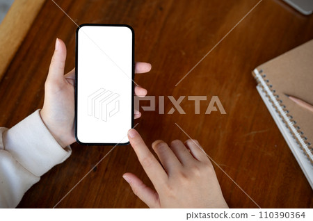 Top view image, A woman using her smartphone at a desk. A white-screen smartphone mockup. 110390364