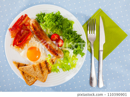 Top view of fried eggs with bacon, sausage and toasts Top view of fried eggs with bacon, sausage and toasts 110390901