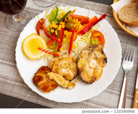 Oven baked hake with vegetable garnish 110390998