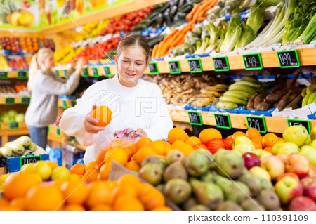 Smiling girl looking for sweet oranges in supermarket 110391109