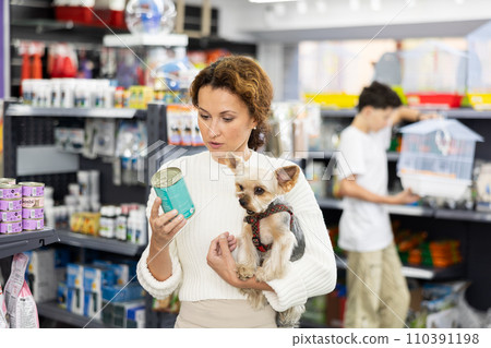 Buyers woman with Yorkshire Terrier choose healthy food and nutrition for pet in tin can Buyers woman with Yorkshire Terrier choose healthy food and nutrition for pet in tin can 110391198
