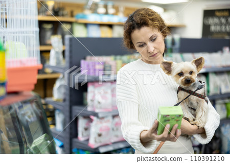 Woman with Yorkshire terrier choosing dry dog food in pet store 110391210