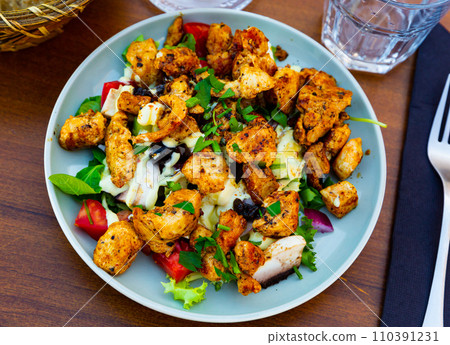 Traditional dish of American cuisine is a warm Caesar salad with fried chicken and champignons 110391231