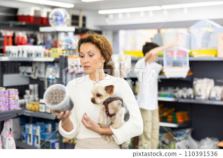 Female owner of Yorkshire terrier choosing dry dog food in pet store Female owner of Yorkshire terrier choosing dry dog food in pet store 110391536