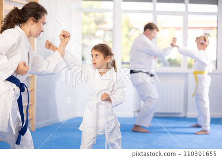 Mom trains daughter to do kicks at karate lessons Mom trains daughter to do kicks at karate lessons 110391655
