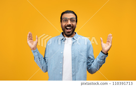 Exuberant man with a beard and glasses, arms raised in a welcoming gesture 110391713