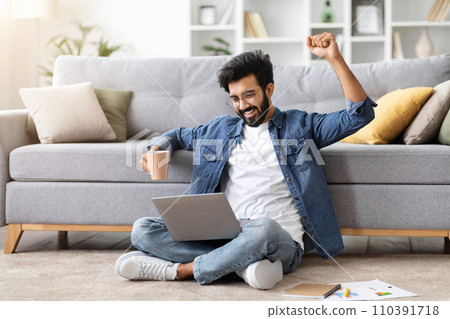 Ecstatic indian man with laptop celebrating victory or good news Ecstatic indian man with laptop celebrating victory or good news 110391718