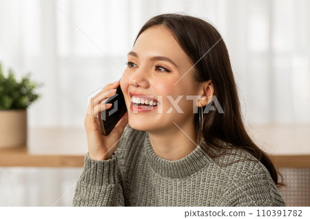 Closeup of happy young woman talking on phone at home Closeup of happy young woman talking on phone at home 110391782