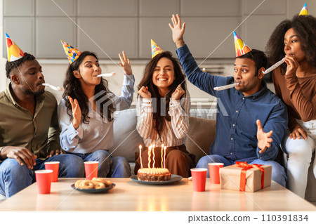 Diverse friends in festive hats making birthday wish indoor Diverse friends in festive hats making birthday wish indoor 110391834