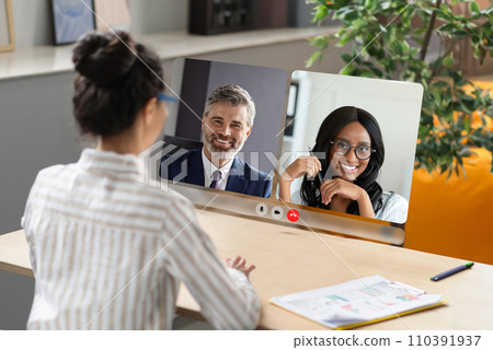 Back view of businesswoman video calling diverse colleagues in office Back view of businesswoman video calling diverse colleagues in office 110391937