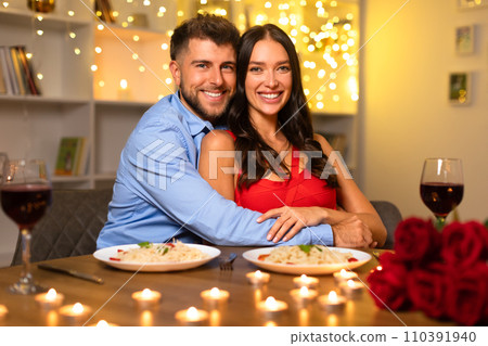 Happy couple embracing at dinner with wine and roses, warm bokeh lights 110391940
