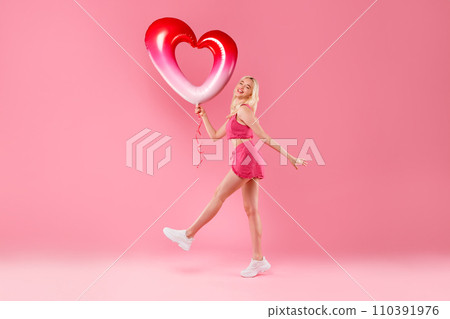 Happy girl dancing with heart balloon in pink 110391976
