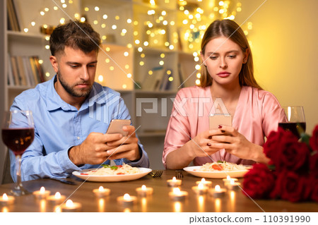 Couple distracted by smartphones during romantic dinner 110391990