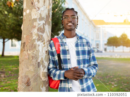 Confident black student guy posing with backpack outside university campus 110392051