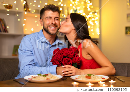 Happy couple at dinner, woman kissing man's cheek 110392195