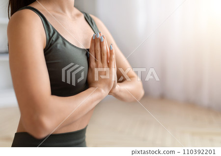 Cropped shot of sporty woman in activewear holding hands in namaste gesture 110392201