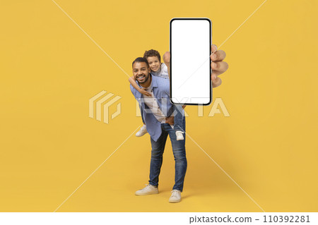 Smiling Black Father And Preteen Son Demonstrating Smartphone With Blank White Screen Smiling Black Father And Preteen Son Demonstrating Smartphone With Blank White Screen 110392281