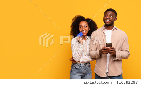 Happy black couple with credit card and smartphone, planning purchase, free space 110392288