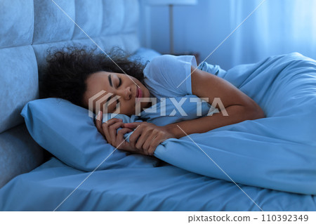 Peaceful black lady asleep napping in domestic bedroom at night Peaceful black lady asleep napping in domestic bedroom at night 110392349