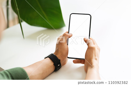 Cropped man hands using cell phone with white empty screen Cropped man hands using cell phone with white empty screen 110392382