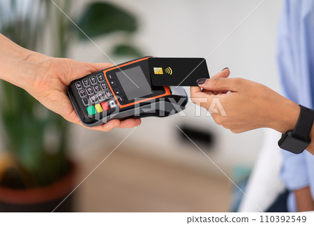 Hands of lady hold black contactless credit card over card reader to complete payment Hands of lady hold black contactless credit card over card reader to complete payment 110392549