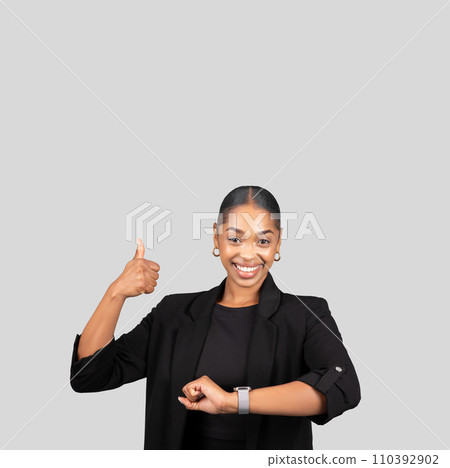 Smiling young African American businesswoman in a black blazer giving a thumbs up Smiling young African American businesswoman in a black blazer giving a thumbs up 110392902