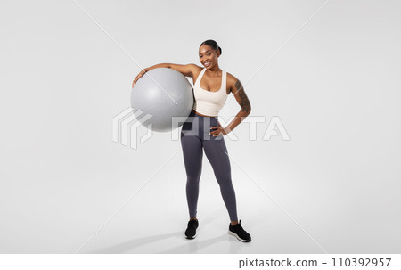 Black fitness woman holds fitness ball over white background 110392957