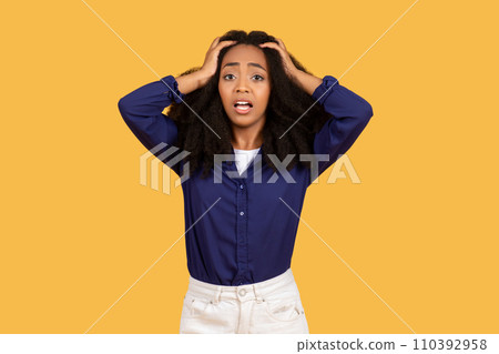 Worried black woman with hands on head against a yellow background 110392958