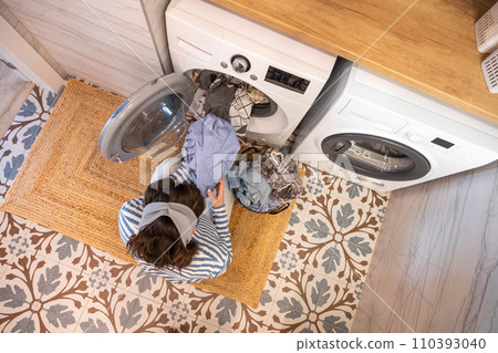 Housewife female taking clean wet clothes fabric from washing machine minimalist bathroom top view Housewife female taking clean wet clothes fabric from washing machine minimalist bathroom top view 110393040