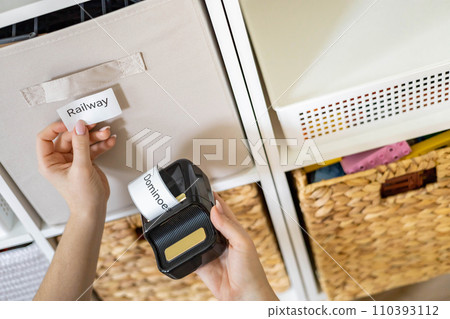 Woman mother applying paper sticker with name title on basket container clean out of childish toys 110393112