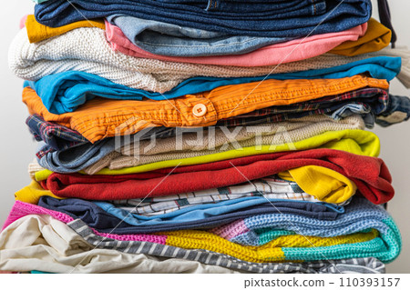 A very tall stack of folded colored clothes for charity, washing, ironing and sorting. 110393157