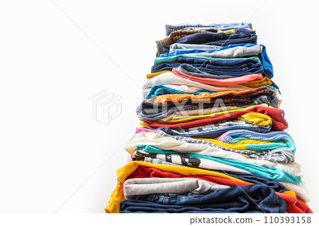 A very tall stack of folded colored clothes for charity, washing, ironing and sorting. A very tall stack of folded colored clothes for charity, washing, ironing and sorting. 110393158