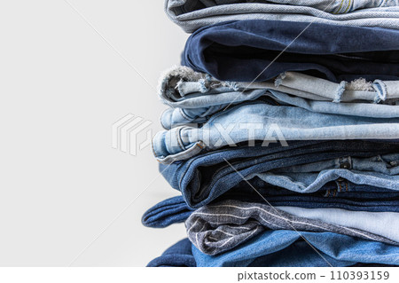 Stack of various shades of blue jeans on white background Stack of various shades of blue jeans on white background 110393159