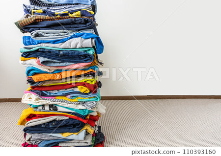A very tall stack of folded colored clothes for charity, washing, ironing and sorting. A very tall stack of folded colored clothes for charity, washing, ironing and sorting. 110393160