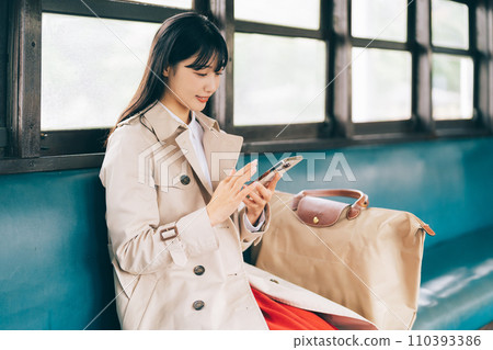 Woman looking at smartphone by train 110393386